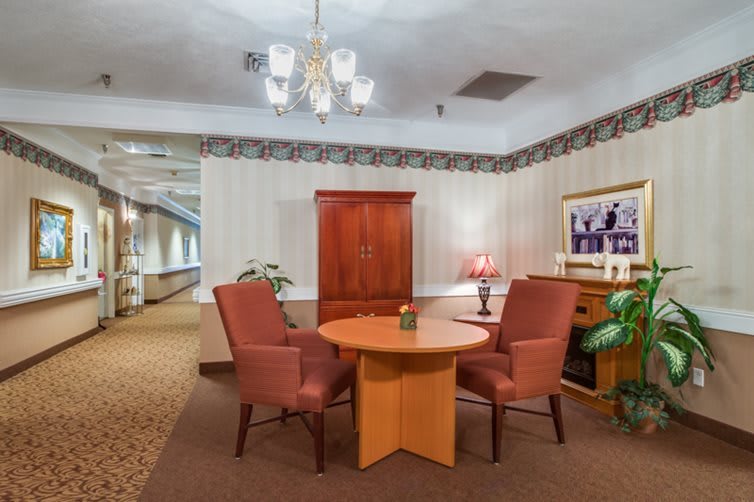 Cozy interior with a round table, two chairs, and decor including a lamp and painting.