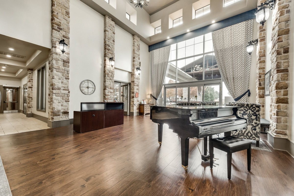 A luxurious living space featuring a grand piano, large windows, and modern decor.