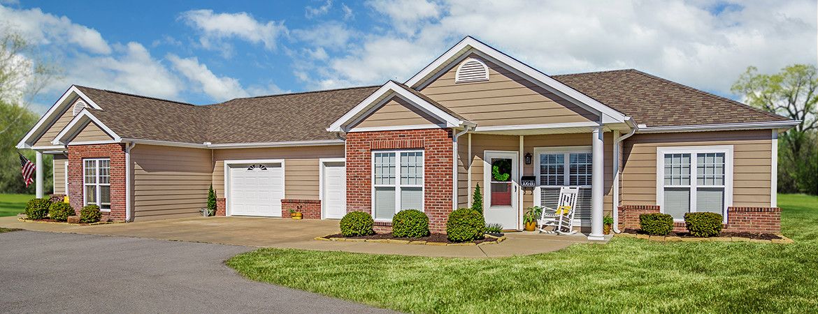 A suburban residential house with a brick facade, garage, and well-maintained front yard.