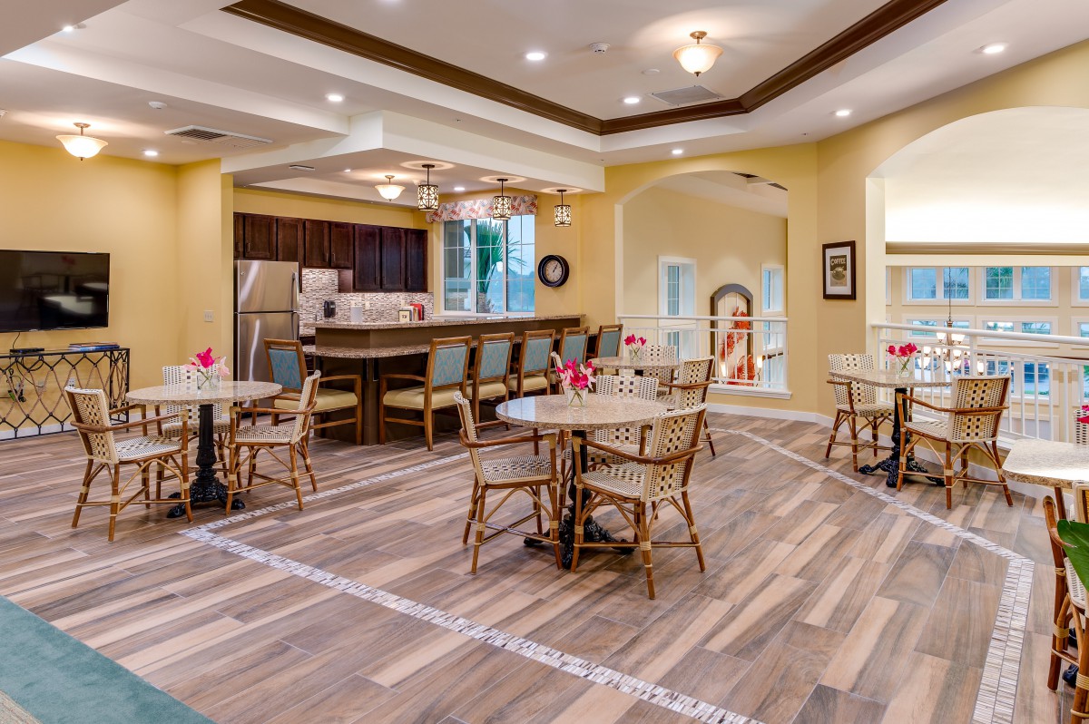 A modern dining area with wooden floors and a view into the kitchen.