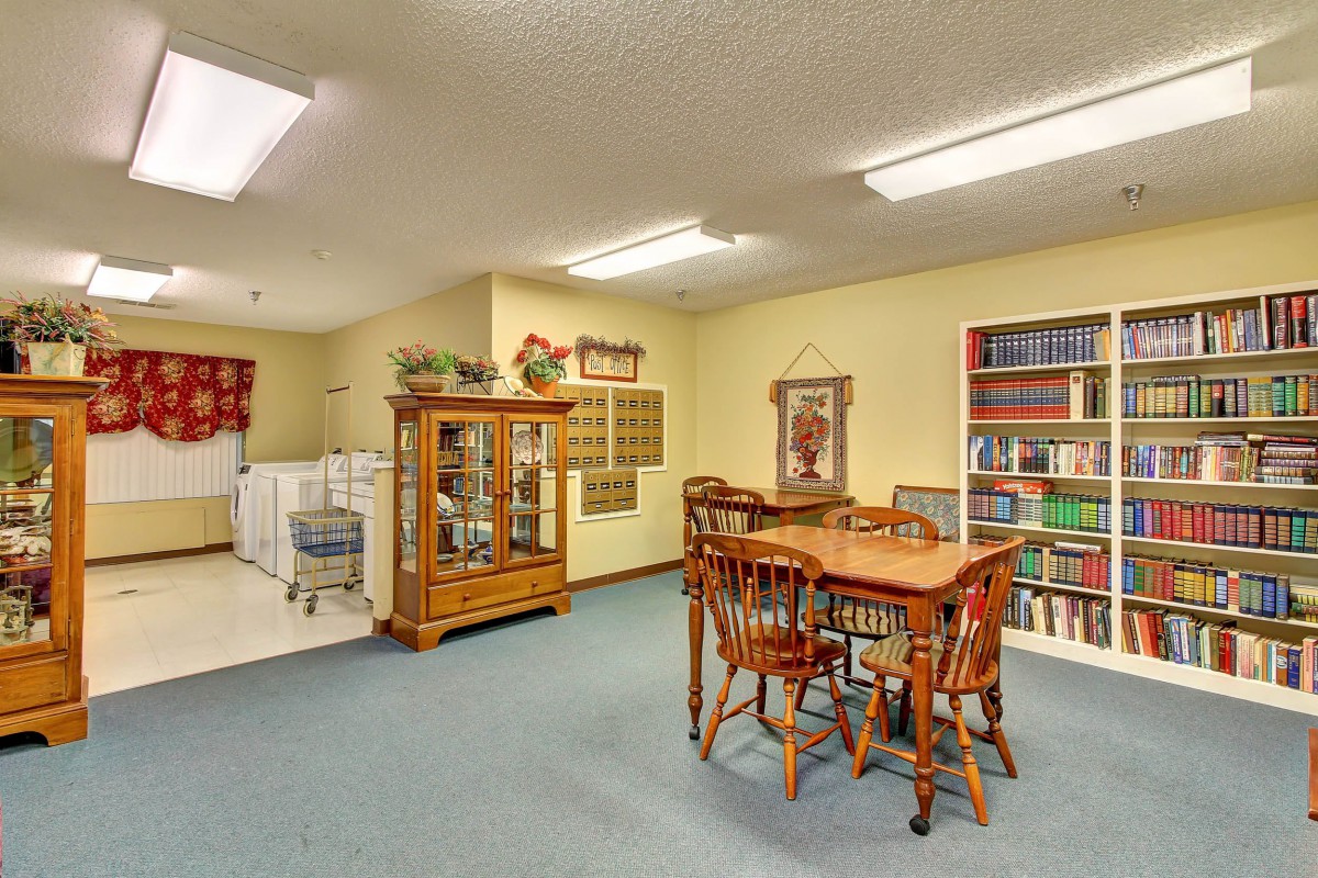 A cozy living room with a dining table, bookshelf, and a display cabinet.