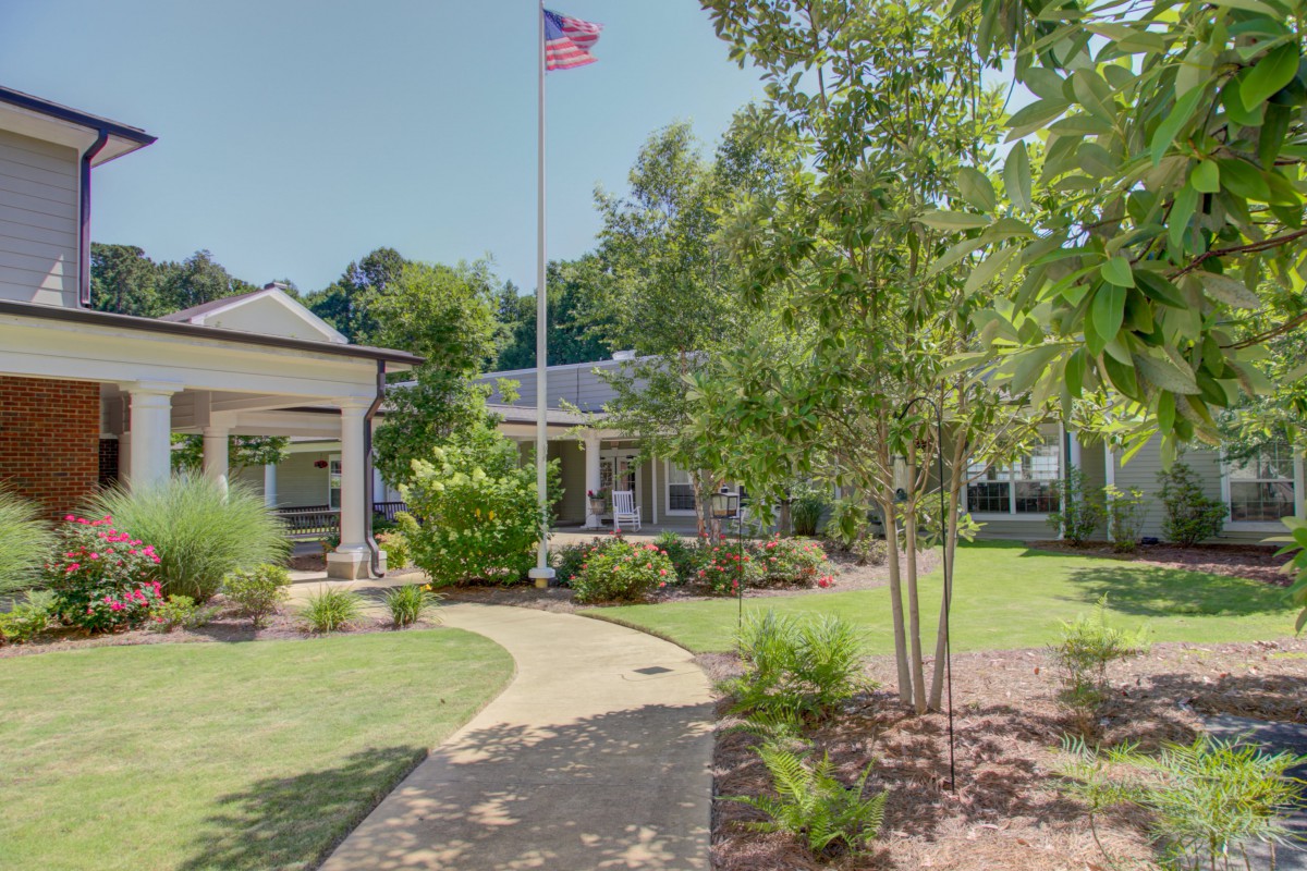A landscaped garden with a pathway leading to a building, featuring a flagpole.