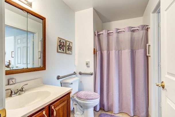 A tidy bathroom with a wooden vanity, mirror, and lavender-themed decor.