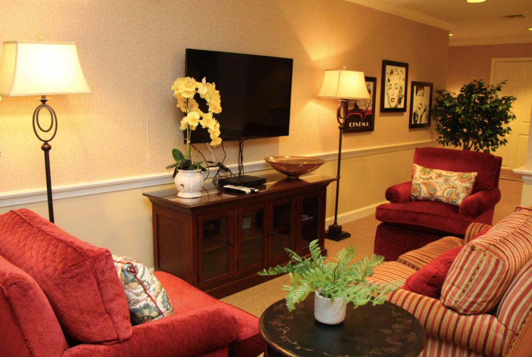 A cozy living room with red sofas, a mounted TV, and decorative plants.