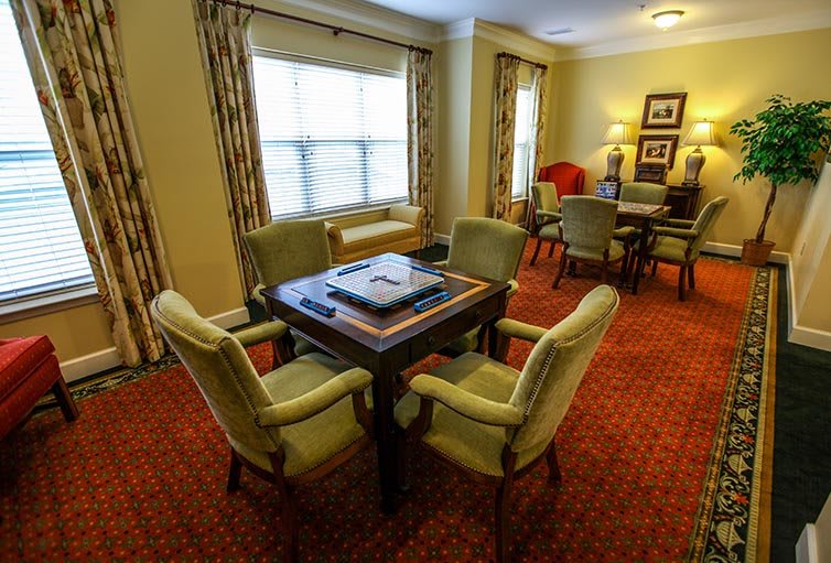 A cozy living room with a card table, chairs, and a carpeted floor.