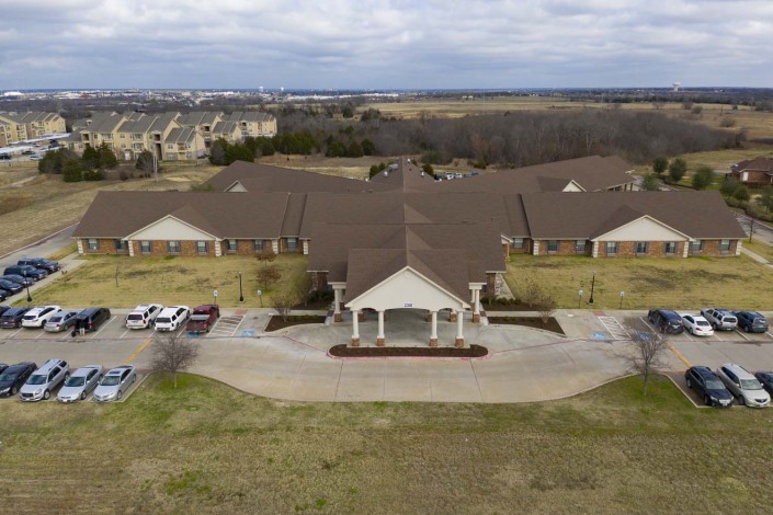 Aerial view of a large suburban building with surrounding landscape.