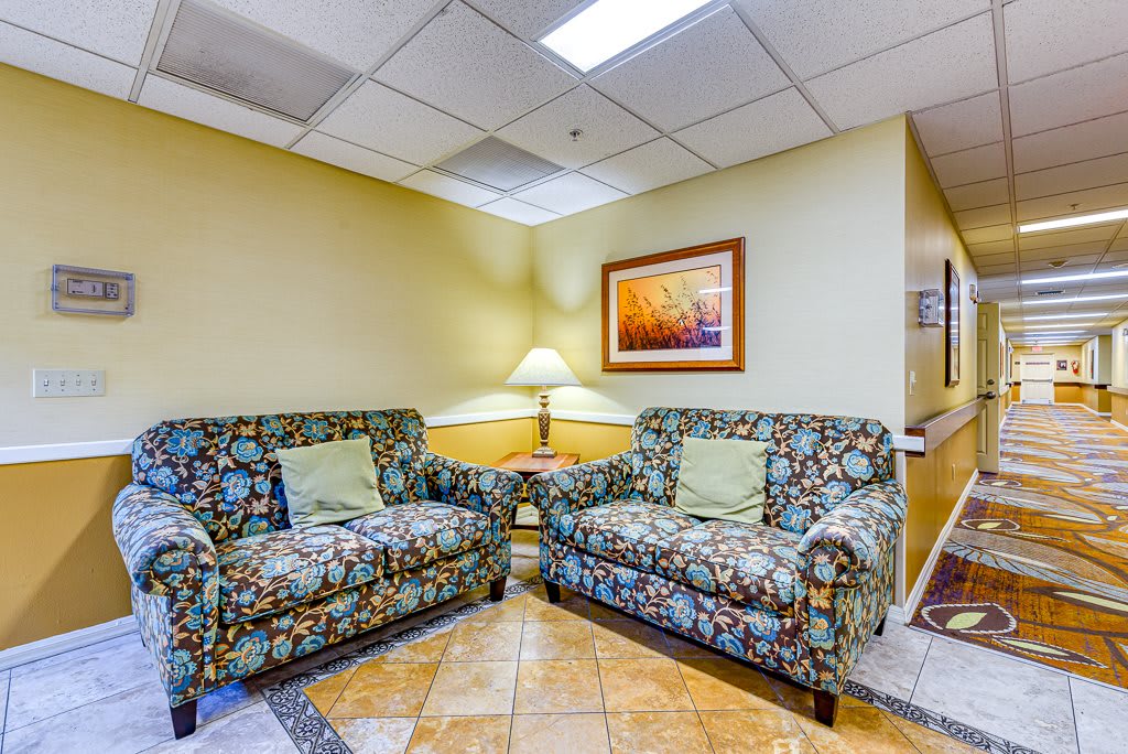 A cozy lobby seating area with patterned couches and a lamp providing warm lighting.