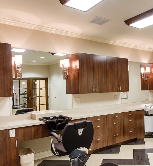 A modern salon interior featuring a barber chair, large mirror, and wooden cabinets.