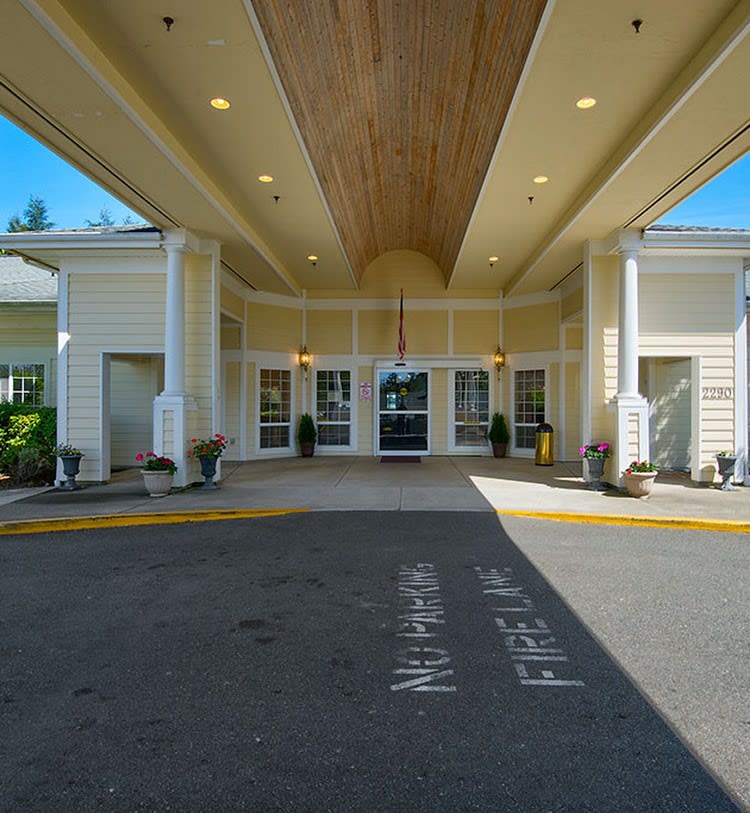 Entrance of a building with a covered driveway and designated fire lane.