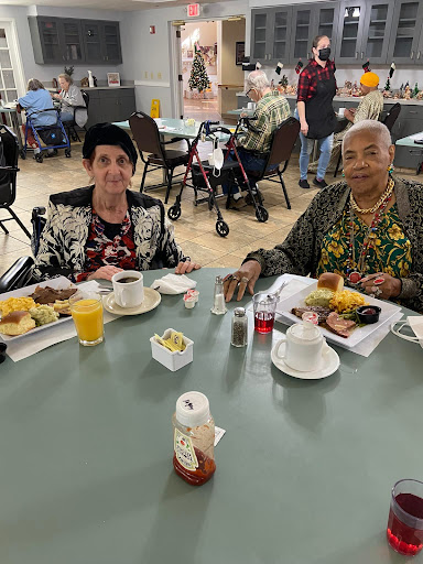 Two friends enjoying a meal together at a community dining area.