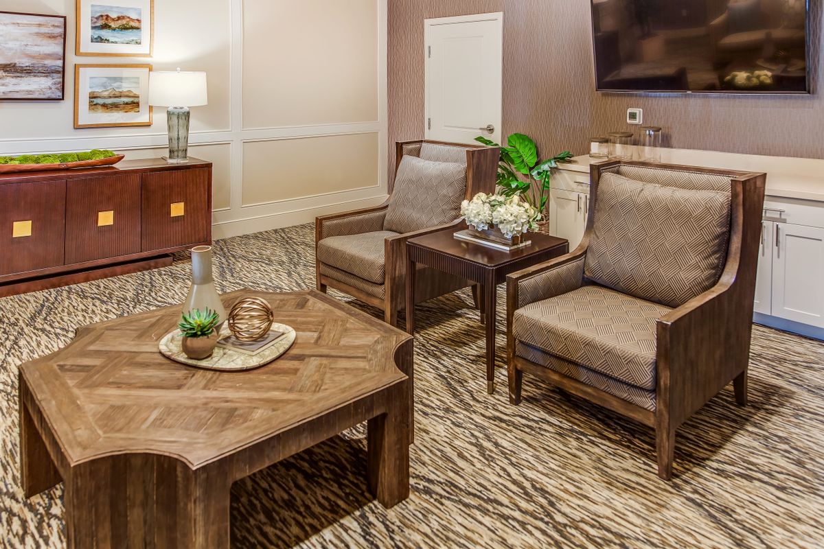 A cozy living room area with comfortable chairs and a wooden coffee table, adorned with decorative items and a potted plant.