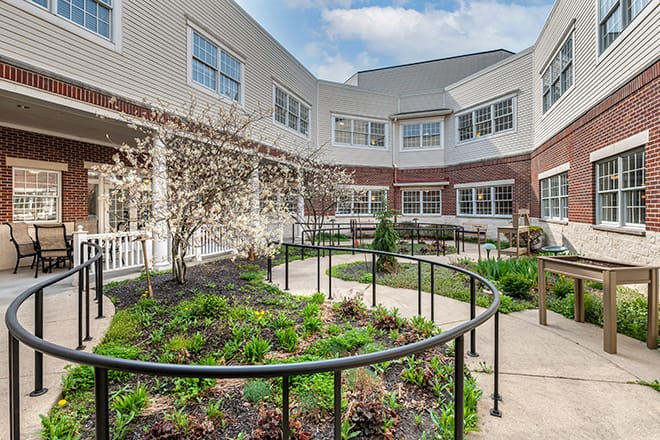 A courtyard featuring a garden with pathways and railings surrounded by a multi-story building.