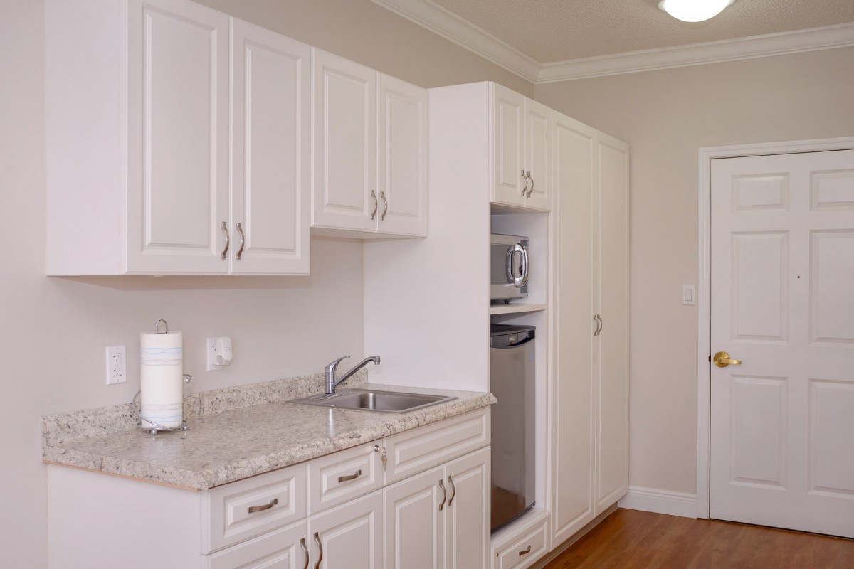 A modern kitchen with white cabinets and built-in appliances.