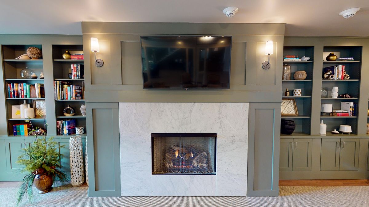 A modern living room with a stylish fireplace, mounted television, and elegant wall sconces.