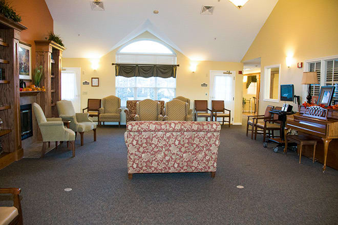 A cozy waiting room featuring an array of chairs and a patterned sofa, with large windows bringing in natural light.