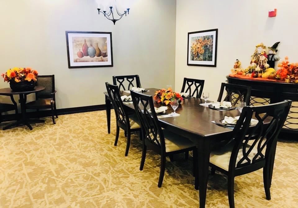 A well-decorated dining room featuring a large table with chairs, artwork on the walls, and a vase centerpiece.