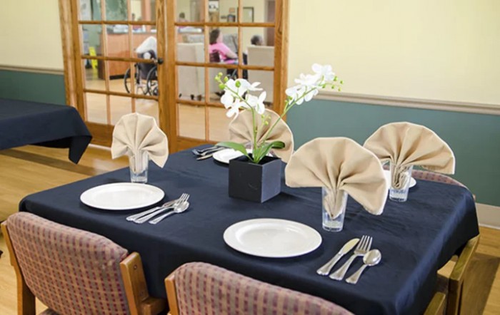Elegantly set dining table with folded napkins and a floral centerpiece.