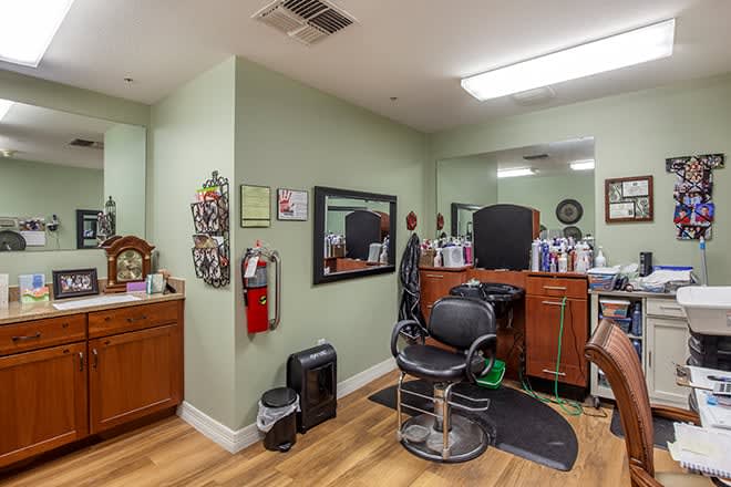 An interior view of a barbershop with a styling chair, mirrors, and hair care products.