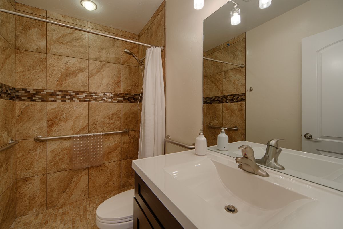 A modern bathroom with tiled walls and a large mirror above the sink.