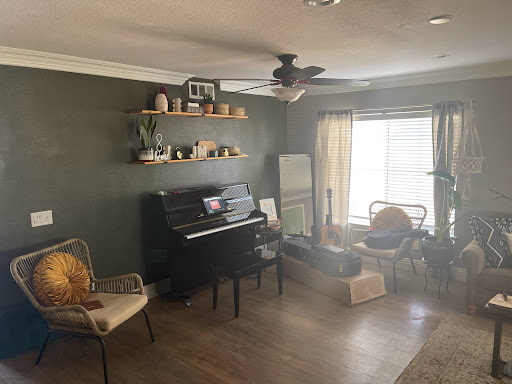 A cozy living room featuring a black piano, stylish shelves with decorative items, and comfortable seating.