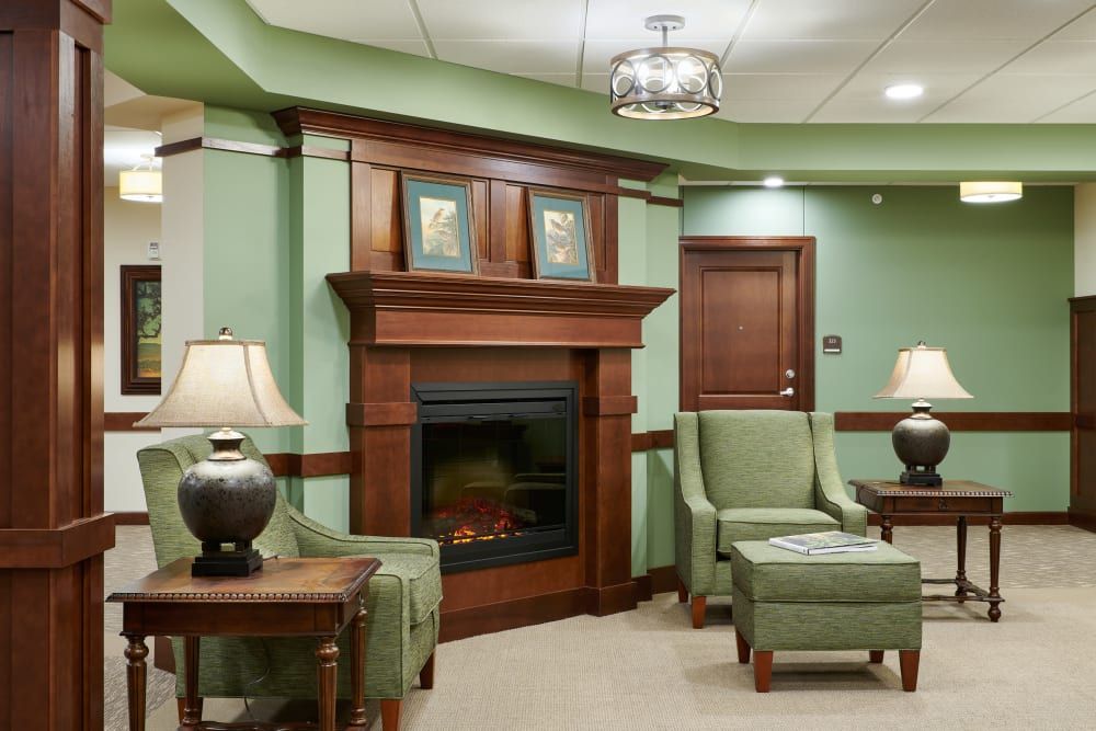 A cozy living room with green walls, featuring a wooden fireplace and comfortable seating.