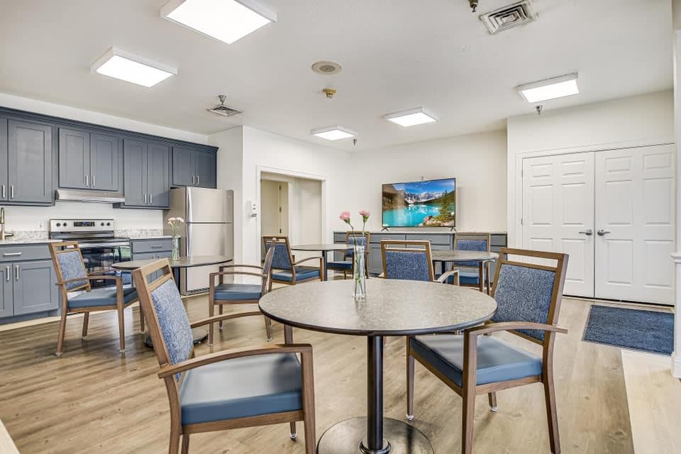 A modern dining and kitchen area with a round table, chairs, and a television.