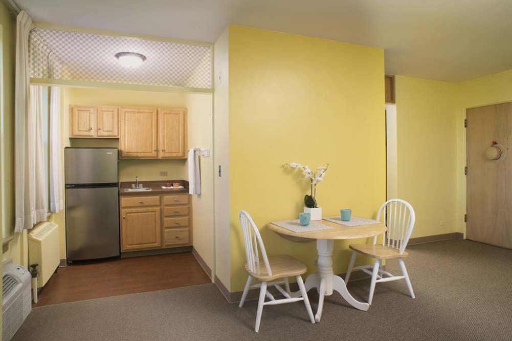 A cozy kitchen with a small dining area featuring yellow walls and wooden furniture.