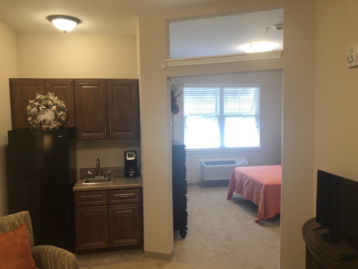 A cozy studio apartment with a small kitchen area and a bright bedroom.