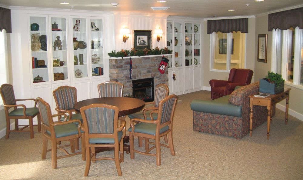 A cozy living room with a fireplace, surrounded by seating and a wooden dining table.