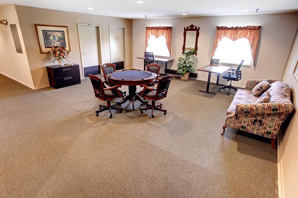 A well-furnished office space featuring a round meeting table, desks, and various chairs.