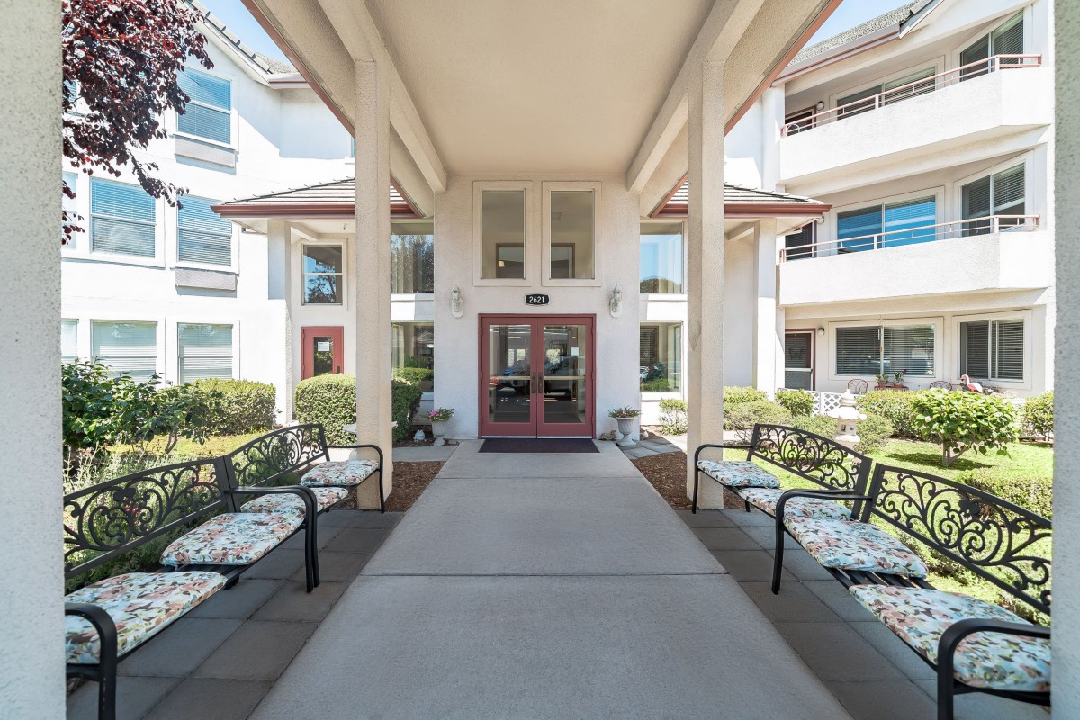 A welcoming building entrance with benches and decorative landscaping.