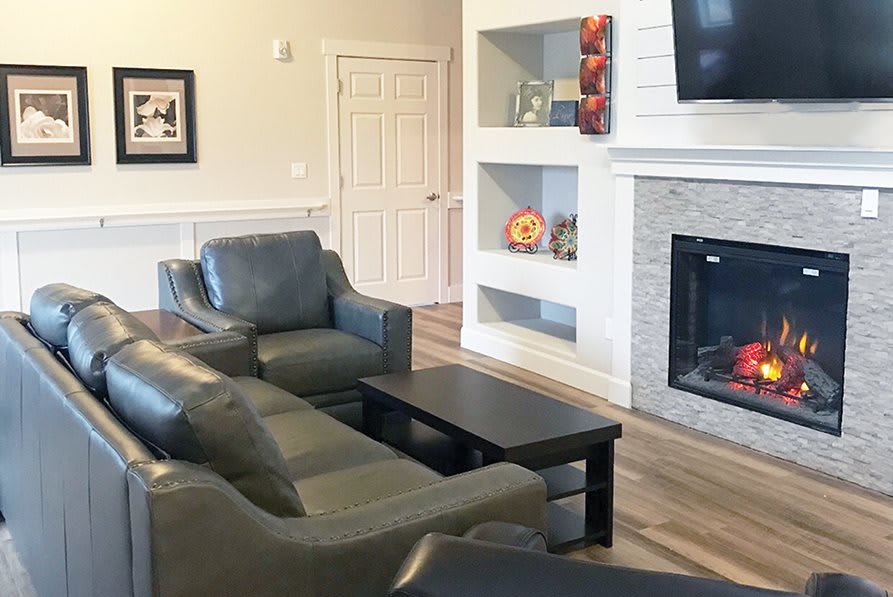 A cozy living room with leather sofas, a coffee table, and a fireplace with built-in shelves.