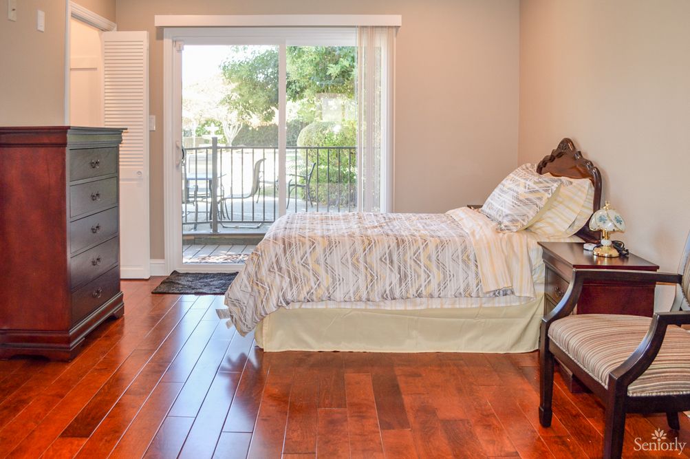 A cozy bedroom with a double bed, hardwood floors, and a sliding patio door letting in natural light.