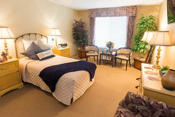 A cozy and well-decorated bedroom with a comfortable bed, chairs, and decorative plants.