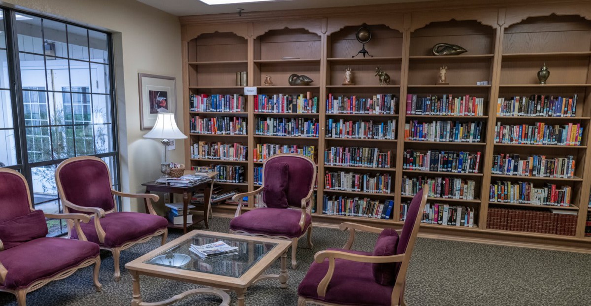 Cozy library reading area with bookshelves, chairs, and a table.