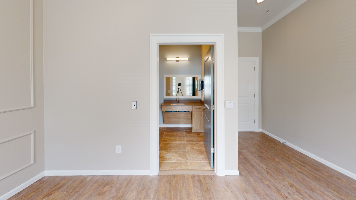 A modern, minimalist bathroom view with wooden flooring and a large mirror above the sink.