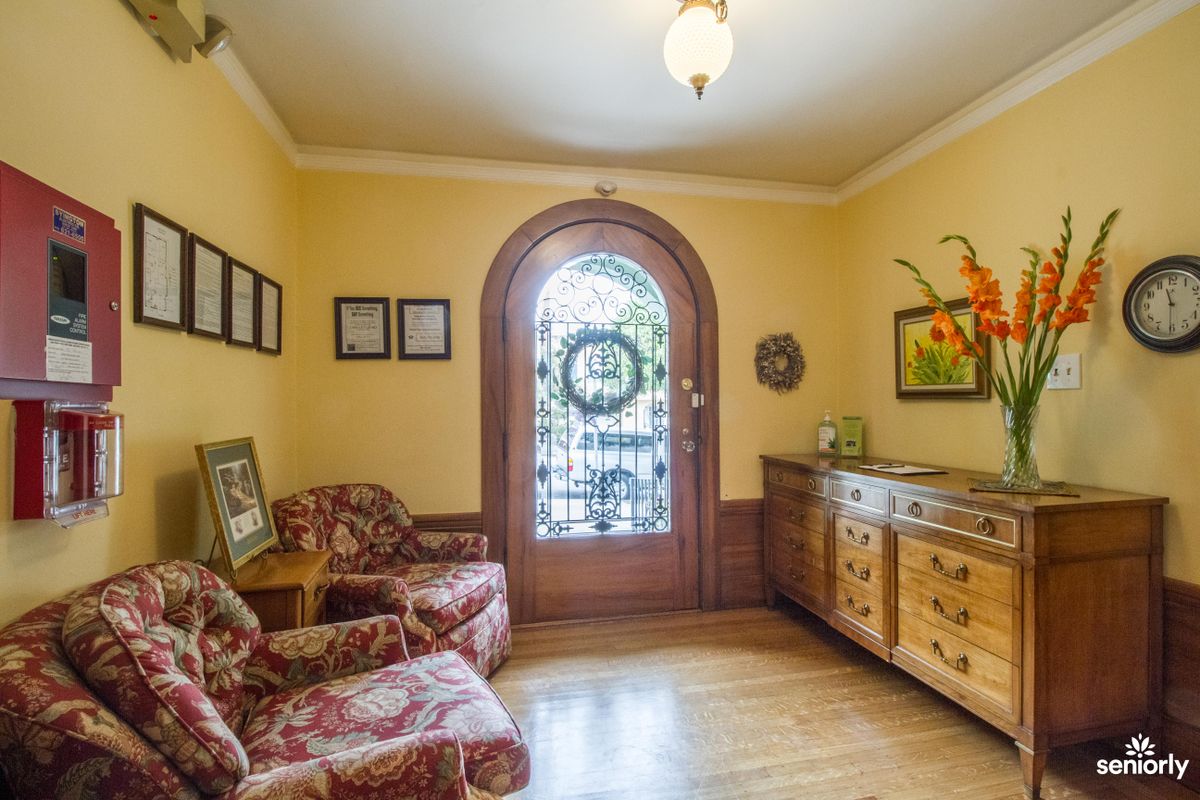 A cozy living room with traditional decor, featuring patterned armchairs, a wooden floor, and a decorative arched door.