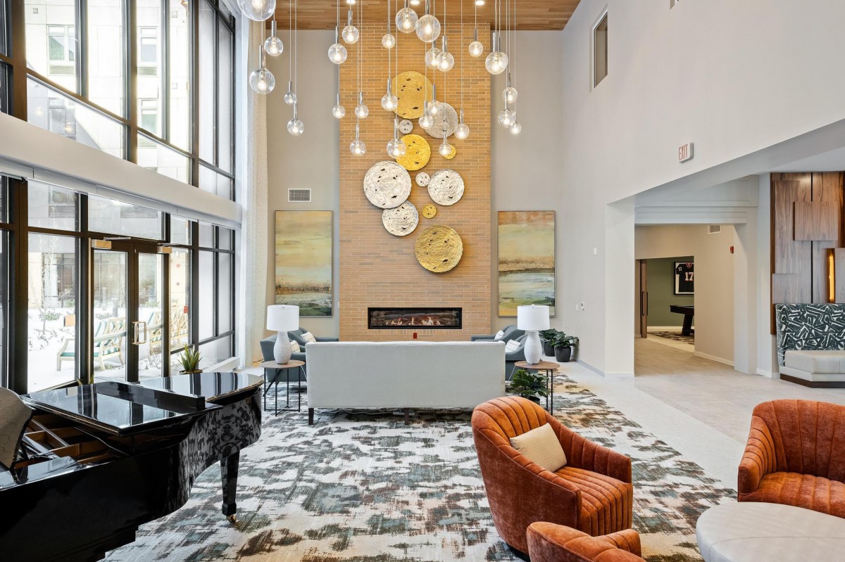A modern lobby featuring a stylish chandelier, grand piano, and contemporary art decor.