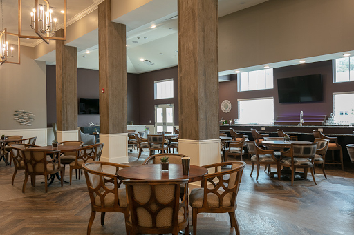 A spacious and modern dining area featuring wooden tables and chairs, complemented by large windows that allow ample natural light.