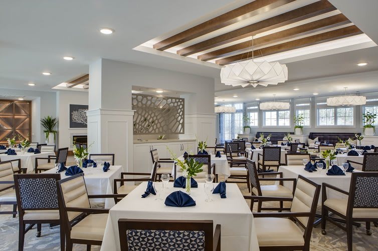 An elegant dining room with neatly arranged tables and chairs, featuring stylish decor and ambient lighting.