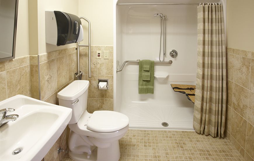 An accessible bathroom with a shower, toilet, and sink equipped with grab bars.