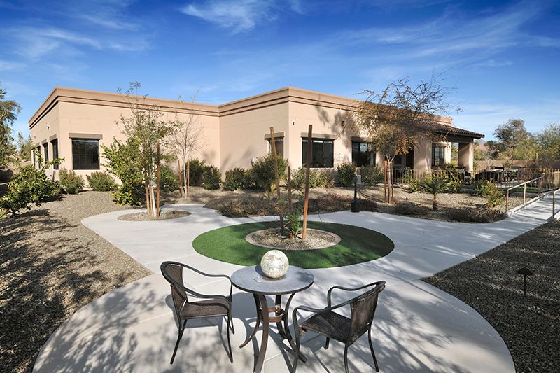 A sunny courtyard with chairs and a table surrounded by desert landscaping.