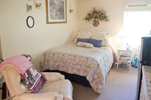 A cozy bedroom featuring a neatly made bed with floral bedding and soft lighting.