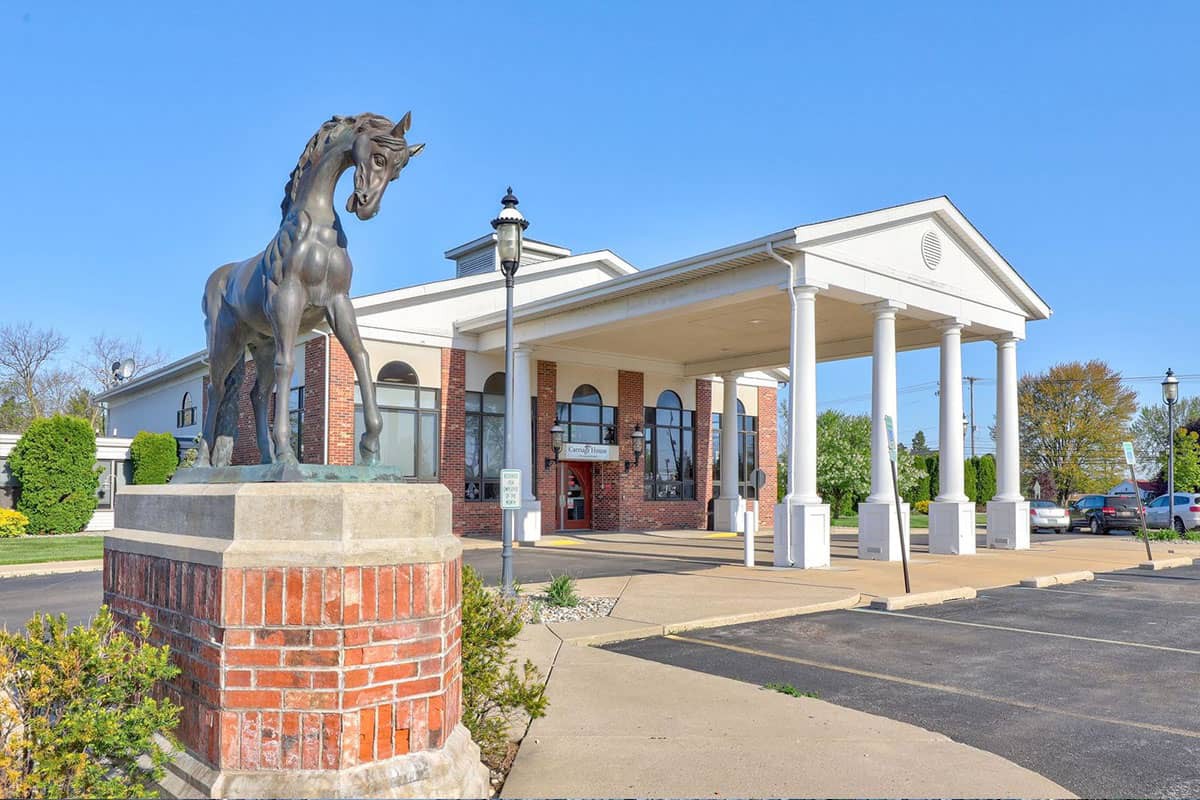 A building entrance with a horse statue and classical columns.