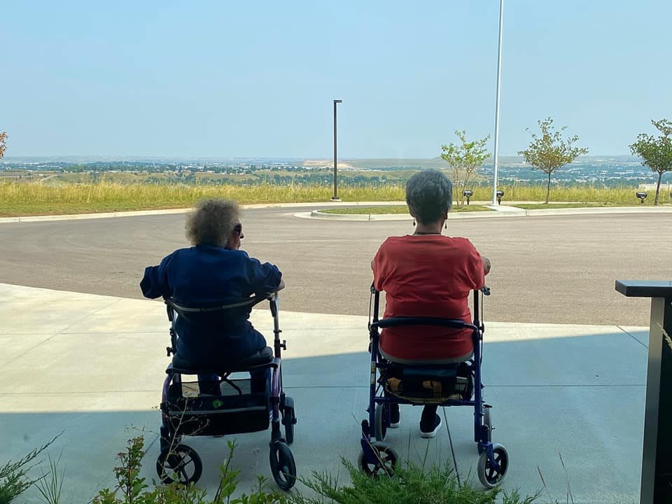 Two people sitting in wheelchairs, enjoying the outdoors.