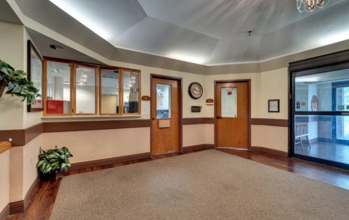 A reception area with wooden doors, a glass window for service, and a wall clock.