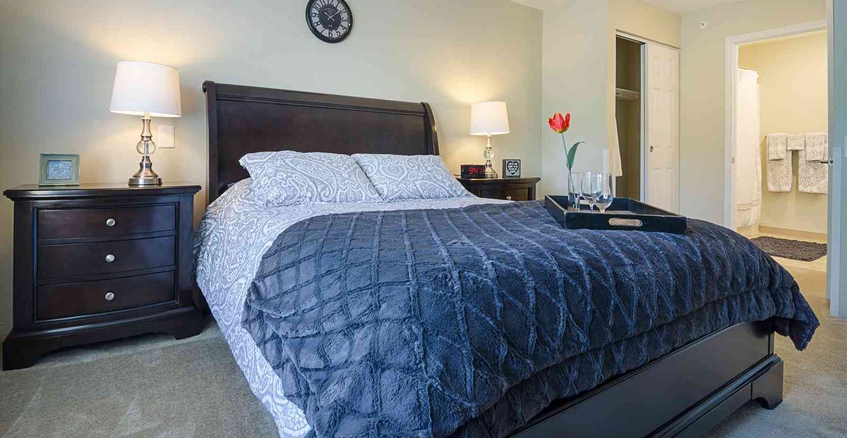A well-decorated bedroom with a neatly made bed and side lamp.
