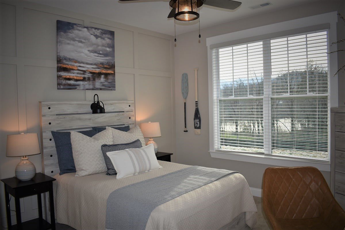 A cozy bedroom featuring a nautical-themed decor with a comfortable bed, wall art, paddle decorations, and a large window with blinds.