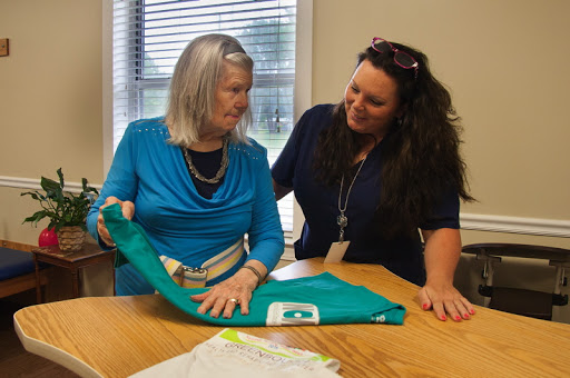 Two women engaged in a friendly conversation while examining a piece of clothing.