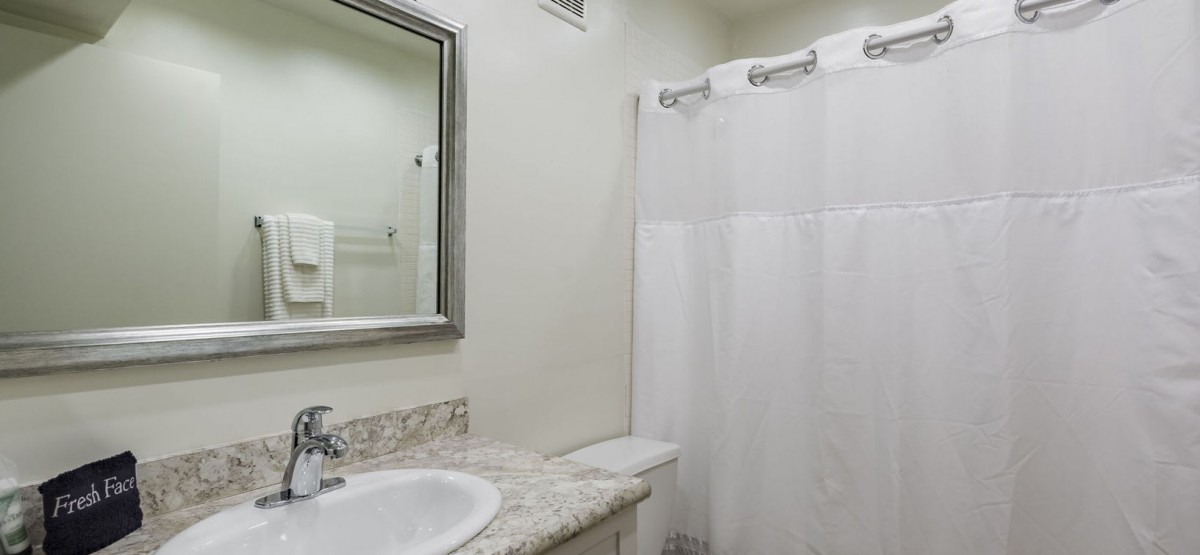 A clean and simple bathroom with a marble countertop and a shower curtain.